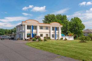 a large white building with blue columns at Rodeway Inn & Suites New Paltz - Hudson Valley in New Paltz