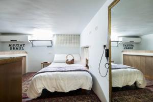 1 dormitorio con 2 camas y espejo en Ahuzat Shaul - Apartment, en H̱adera