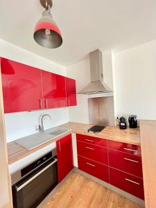 een keuken met rode kasten en een wastafel bij PoNSARDIN - Bel appartement avec balcon et Parking in Reims