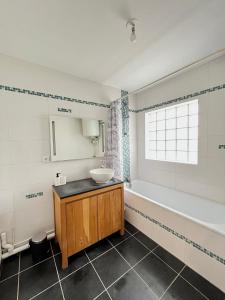 een badkamer met een wastafel en een bad bij PoNSARDIN - Bel appartement avec balcon et Parking in Reims