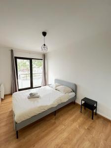 een witte slaapkamer met een bed en een raam bij PoNSARDIN - Bel appartement avec balcon et Parking in Reims
