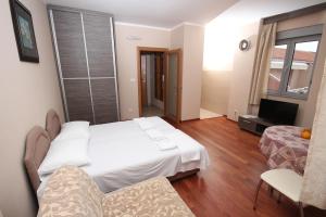 1 dormitorio con 1 cama blanca y sala de estar en Apartments Oaza 2, en Petrovac na Moru