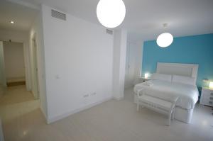 een witte slaapkamer met een wit bed en een blauwe muur bij Livingtarifa Sugar in Tarifa +22 foto's