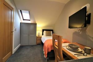 Schlafzimmer mit einem Bett, einem Schreibtisch und einem TV in der Unterkunft Signature - Linden Cottage Room 4 in Airdrie