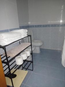 a bathroom with a toilet and a shelf with towels at Piso Casa Reina Un lugar cerca del mar y el puerto in Gandía