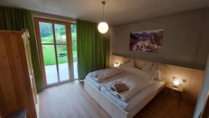 ein Schlafzimmer mit einem weißen Bett und einem großen Fenster in der Unterkunft Kieferhof in Iselsberg