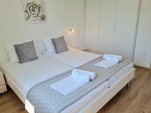 2 łóżka w sypialni z białymi ścianami i drewnianą podłogą w obiekcie Apartman Maslina w Krku