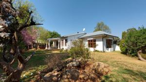 a white house with a garden in front of it at Bluebell Country House in Dullstroom