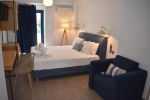 a bedroom with a bed and a blue chair at Christina Studios & Apartments in Parga