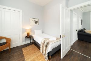 a white bedroom with a bed and a chair at The Gate Lodge in Broughty Ferry