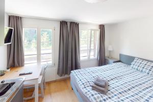 1 dormitorio con cama, escritorio y lavamanos en Rössli Self Check in 24-7 Free Parking, en Unterägeri