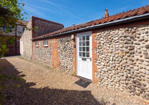 a stone cottage with a white door and a stone wall at The Anchorage in Sheringham