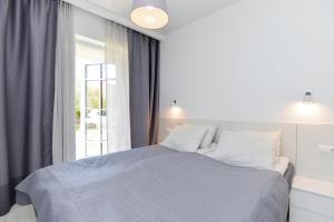 a white bedroom with a large bed and a window at Apartment Amber White in Nida