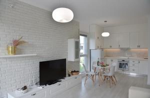 uma cozinha branca com uma televisão e uma mesa com cadeiras em Valamar Apartament em Durrës