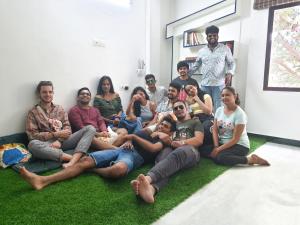 a group of people sitting on the grass in a room at Eness Hostels Pondicherry in Puducherry
