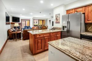 une cuisine avec des armoires en bois et un réfrigérateur en acier inoxydable dans l'établissement Lionsquare Lodge North #294 condo, à Vail