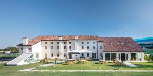 un grand bâtiment blanc avec des tables de pique-nique et des tables dans l'établissement Nomad Hostel, à Trévise