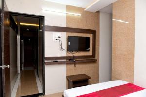 a bedroom with a bed and a tv on the wall at Nivant Lodge in Solapur