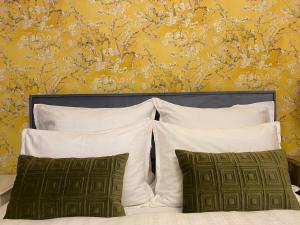 1 cama con almohadas blancas y pared amarilla en NaNa Flat, en Praga