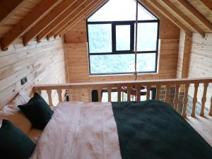 1 dormitorio en una cabaña de madera con una ventana grande en LİMCORA DAĞEVLERİ&BUNGALOW, en Rize