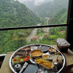 a tray of food on a table with a view at LİMCORA DAĞEVLERİ&BUNGALOW in Rize