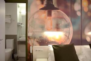 a large glass lamp hanging over a bed in a bathroom at Best Western Hotel Le Montparnasse in Paris