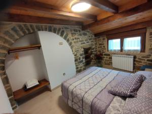 a bedroom with a bed and a stone wall at CASA PESCA VERA in Senegüé