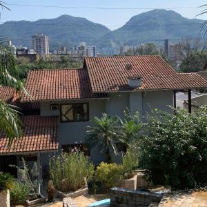 uma casa com telhados vermelhos com montanhas ao fundo em Pousada DRIRIOS HOUSE em Jaraguá do Sul