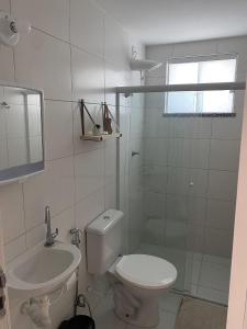 a white bathroom with a toilet and a sink at Apt no Cond. Resort Villa das Águas in Atalaia