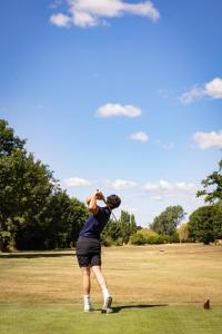 a man swinging a golf club on a field at Avisford Park Hotel in Arundel