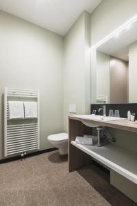 een badkamer met een toilet, een wastafel en een spiegel bij Hotel Amfora in Poperinge