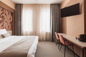 ein Hotelzimmer mit einem Bett, einem Schreibtisch und einem TV in der Unterkunft Hotel Amfora in Poperinge