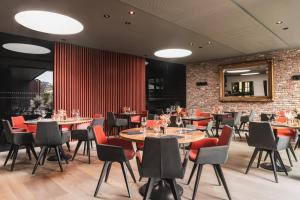 a restaurant with tables and chairs and a brick wall at Hotel Amfora in Poperinge