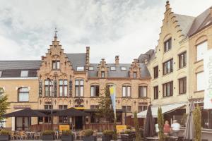 ein Gebäude mit Tischen und Sonnenschirmen davor in der Unterkunft Hotel Amfora in Poperinge