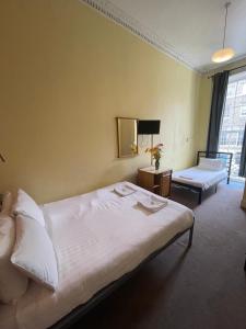 1 dormitorio con 1 cama blanca grande y 1 silla en Thanet Hotel Annex en Londres