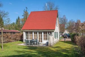 una casa con techo rojo, mesa y sillas en Vakantiepark Hellendoorn en Hellendoorn