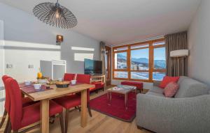 a living room with a couch and a table and chairs at travelski home premium - Résidence Edenarc 5 stars in Arc 1800