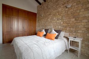 una camera da letto con un grande letto bianco con cuscini arancioni di Villa Los Volcanes a El Charco