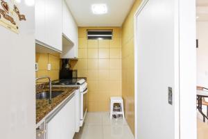 kuchnia z białymi urządzeniami i żółtymi płytkami w obiekcie Apartamento Floripa w mieście Florianópolis