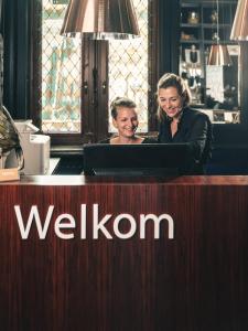 two women sitting at a desk with a laptop at Hotel Amfora in Poperinge