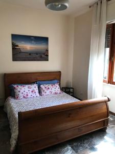 a bedroom with a wooden bed with pink pillows at Casetta dei fiori in Livorno