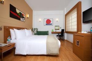 钱德加尔Lemon Tree Hotel Chandigarh的酒店房间里有一张白色的大床和一张书桌