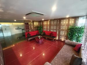 a living room with red couches and plants at Boulevard by Design Hotel Chennai in Chennai