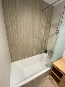 a white bath tub in a bathroom with wooden walls at Premium Lelle Waterfront Resort Bonnie in Balatonlelle