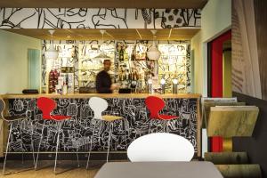 a bar with red chairs and a black and white wall at ibis Hotel Brussels Airport in Diegem +67 photos