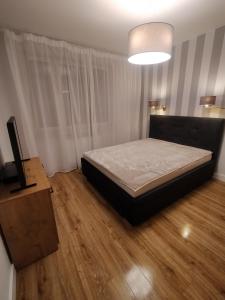 a bedroom with a bed and a television on a wooden floor at Fajny apartament z parkingiem, obok metra. in Warsaw