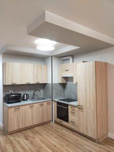 an empty kitchen with wooden cabinets and a sink at Fajny apartament z parkingiem, obok metra. in Warsaw