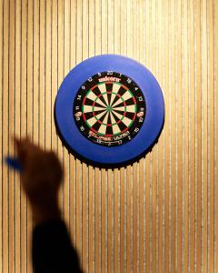 a man pointing at a dartboard on a wall at Hótel Kría in Vík
