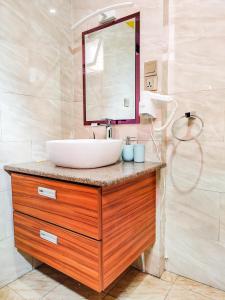 La salle de bains est pourvue d'un lavabo et d'un miroir sur un comptoir. dans l'établissement Valiha Hotel Antananarivo, à Antananarivo
