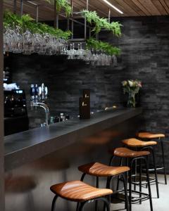 a bar with leather stools and a counter with plants at Hótel Kría in Vík